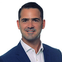 Speaker at a conference, dressed in a suit and tie.