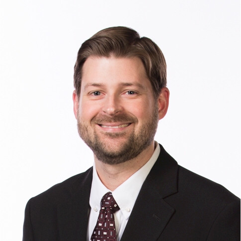 Speaker at a business conference, wearing a suit and tie
