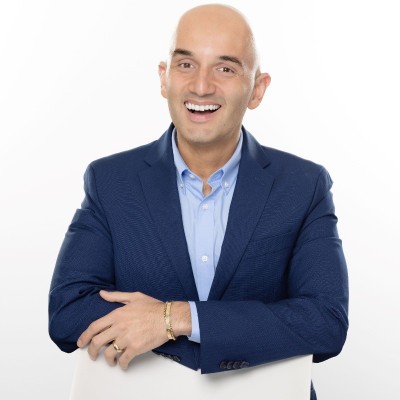 Professional speaker in a blue suit smiling confidently.